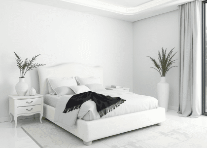 Large white bed in a minimalist natural bedroom, featuring black and white vases, embodying Scandinavian and Japandi design elements for a modern, zen atmosphere.