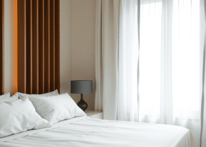 A cozy bedroom featuring a bed with pillows, positioned next to a window adorned with white curtains, embodying white room decor and dream bedroom inspiration for apartment living.